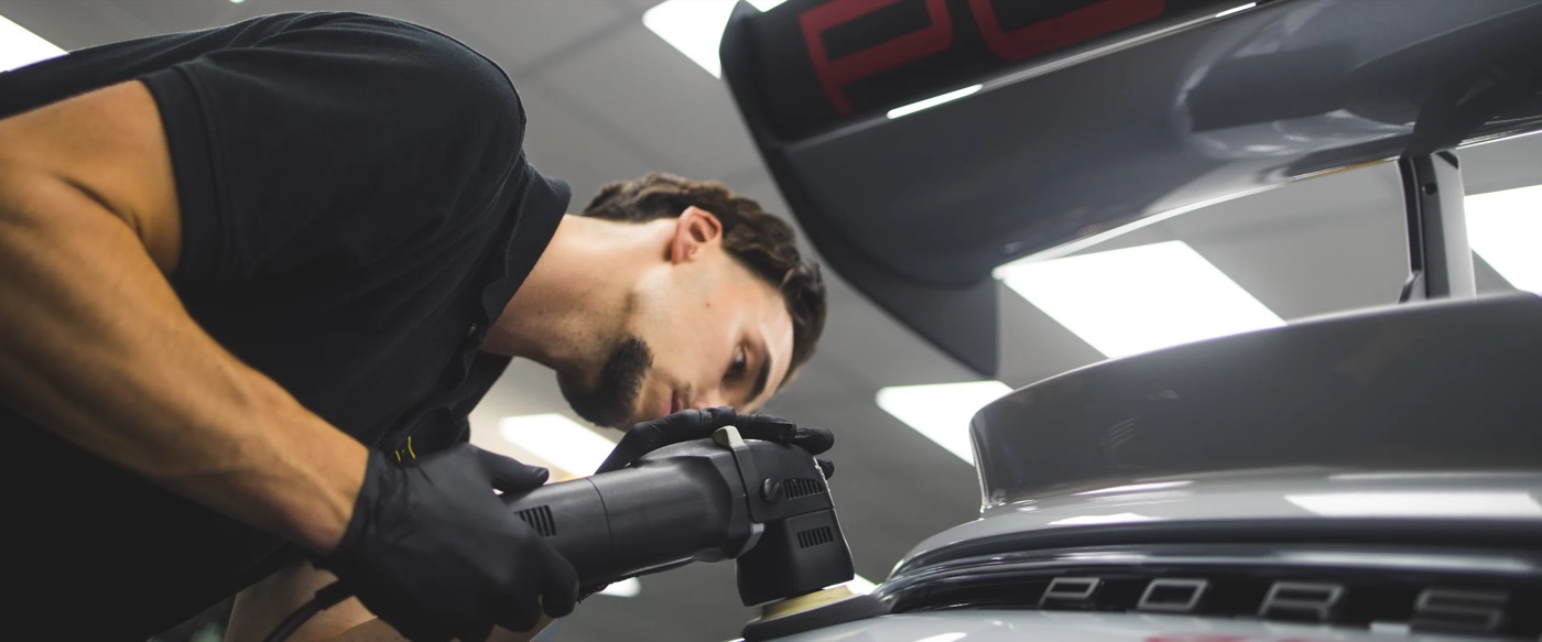 Detailer polijst de lak van een Porsche met een polijstmachine