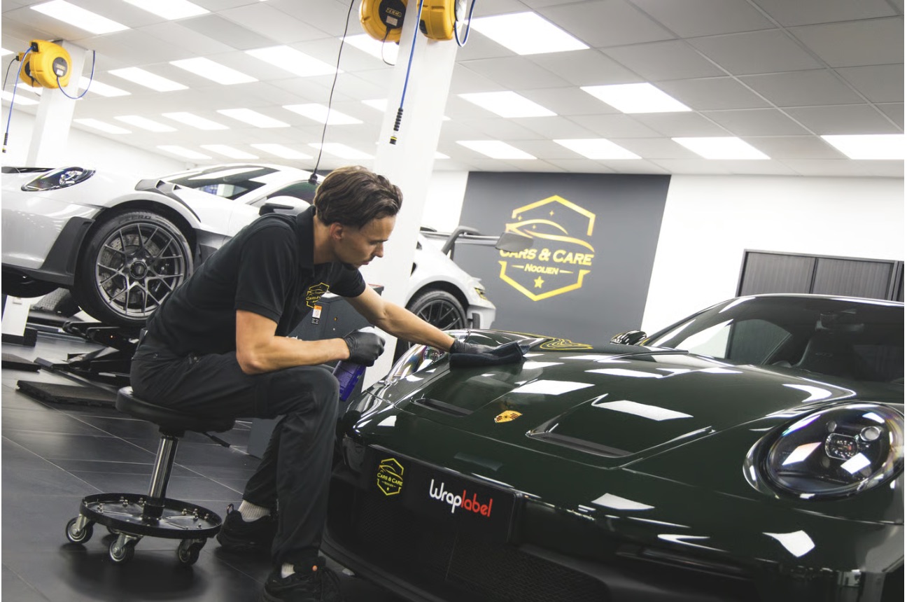 Detailer polijst de motorkap van een groene Porsche